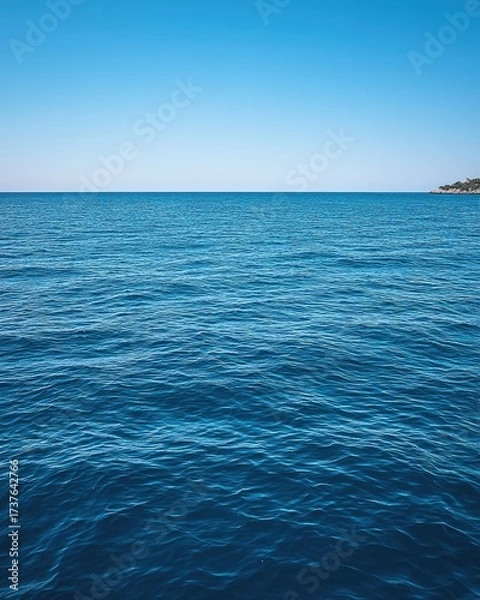 Fototapeta Calm blue ocean meets cloudless sky. Small island on horizon