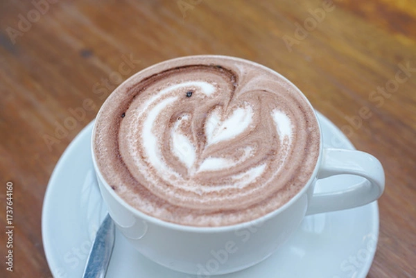 Obraz A cup of coffee with latte art on a wooden table