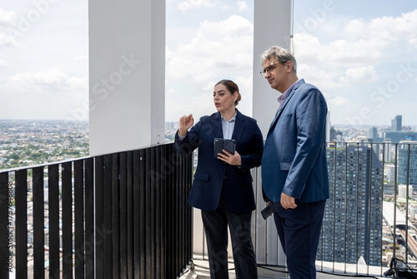 Fototapeta Two business people use tablet computer at rooftop office and city background	