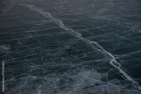 Fototapeta Frozen lake surface with natural ice cracks.