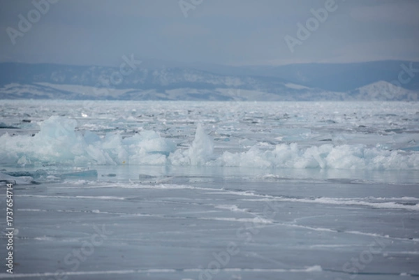 Fototapeta Frozen lake with scattered ice formations and mountains
