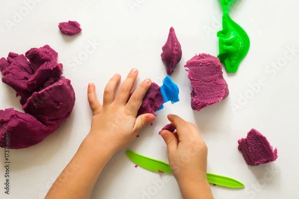 Fototapeta Child's hands with colorful clay. Toddler playing and creating toys from play dough. Boy molding modeling clay. Art therapy for anxious children, cure for stress free