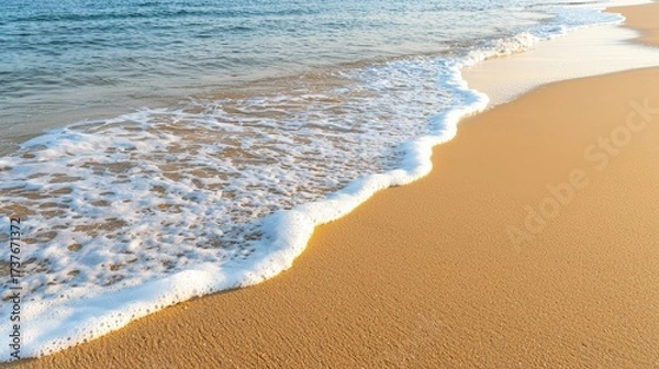 Fototapeta An enchanting beach landscape during sunset, characterized by gentle waves washing over a smooth shoreline. The vibrant colors of the sunset beautifully contrast with the soft textures of the sand,