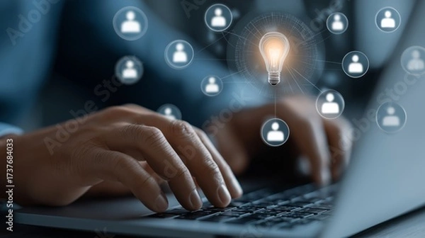 Fototapeta A person is typing on a laptop with a light bulb on the screen