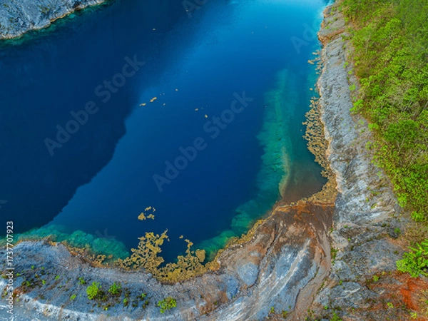 Fototapeta Aerial view beautiful The reflection of the blue sky in the emerald green pond.
Emerald green pond at an old mine. 
Pine trees line the side of an emerald green pond.
blue water blue sky background.