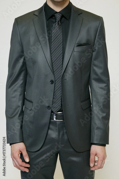 Obraz Man in a stylish gray suit with a black shirt and striped tie.