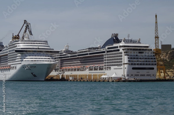 Fototapeta Modern cruise ship cruiseship liner being modernized over-hauled repaired refitted maintenanced by shipyard in Malta with dock and cranes