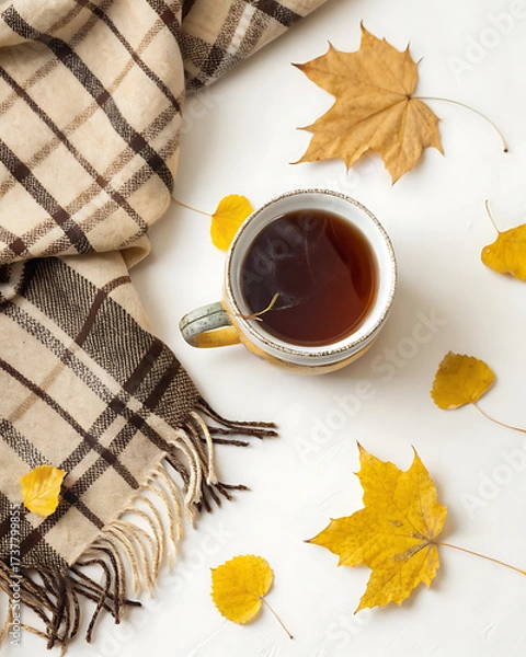 Fototapeta Cozy composition in flat lay style, golden autumn. A cup of steaming tea, a soft blanket and scattered yellow leaves