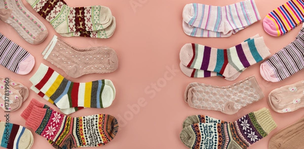 Fototapeta A panoramic background of multicolored socks. The colorful socks are scattered on a pink background. There is space for text.