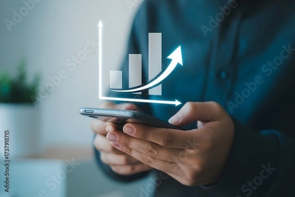 Fototapeta Close up of a person using a smartphone with a rising bar graph representing business growth and financial success for mobile banking and investment apps