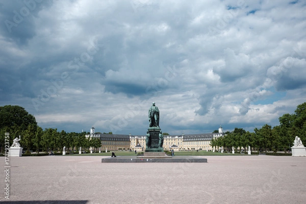Fototapeta A wide, symmetrical view of the Schlossplatz (Palace Square) in Karlsruhe, Germany, featuring the central Großherzog-Karl-Friedrich-Denkmal monument.