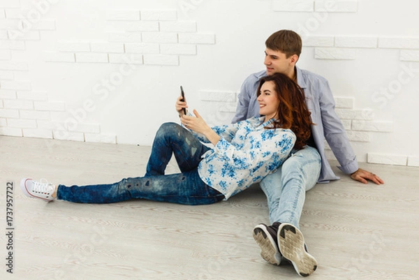 Fototapeta Dreamy couple lying on floor in empty room and looking up, imagine future interior design project, white background.