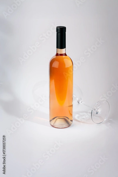 Fototapeta Wine bottle mockup with elegant design, showcasing a vibrant rose color, accompanied by a tilted glass, creating a sophisticated ambiance for branding and marketing purposes