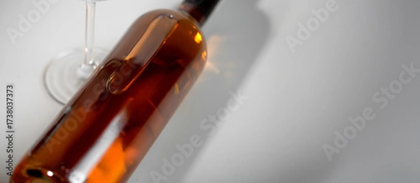 Fototapeta Wine bottle mockup with elegant glass, showcasing rich amber liquid and soft reflections, ideal for branding and design projects with copy space
