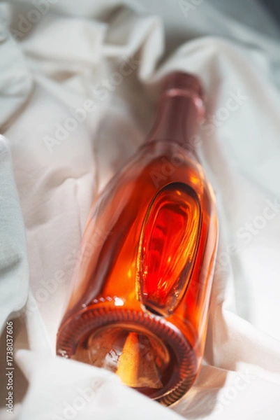 Fototapeta Wine bottle mockup with elegant design resting on soft fabric, showcasing rich amber color and unique shape, ideal for branding and marketing concepts