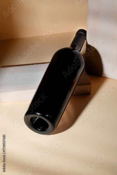 Fototapeta Elegant Red wine bottle mockup positioned on a minimalist surface with soft lighting, showcasing sleek design and modern aesthetics for creative branding concepts