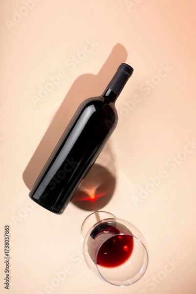 Fototapeta Wine bottle mockup with glass of red wine on soft peach background, showcasing elegant design and rich color, perfect for branding and marketing concepts