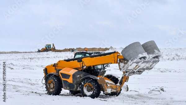 Fototapeta Installation of canalization rings with machine telehandler in winter conditions