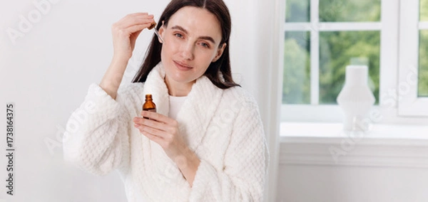 Fototapeta Woman enjoying a relaxing skincare routine in a modern bathroom at home