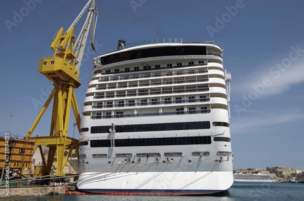 Fototapeta Modern cruise ship cruiseship liner being modernized over-hauled repaired refitted maintenanced by shipyard in Malta with dock and cranes