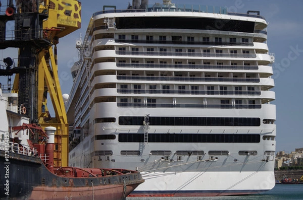 Fototapeta Modern cruise ship cruiseship liner being modernized over-hauled repaired refitted maintenanced by shipyard in Malta with dock and cranes