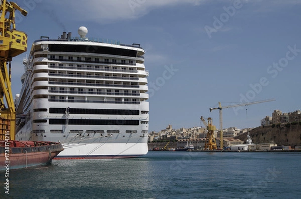 Fototapeta Modern cruise ship cruiseship liner being modernized over-hauled repaired refitted maintenanced by shipyard in Malta with dock and cranes