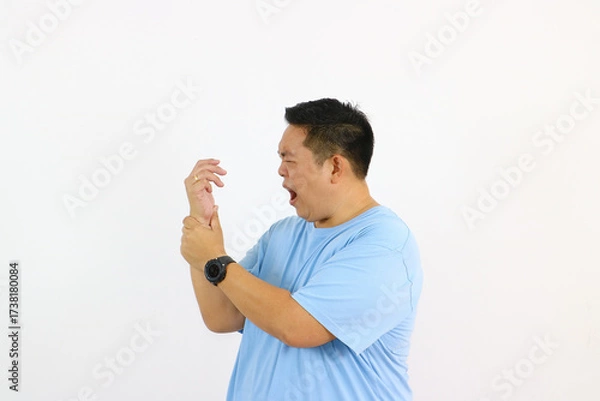 Fototapeta Man grimacing in pain holding his wrist with white background