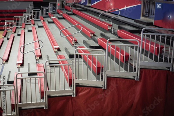 Fototapeta Red cushioned bleacher seats with gray safety rails, visible section signage. Team banners, seating gaps highlight thoughtful stadium planning, inclusive college design features in Dallas, Texas