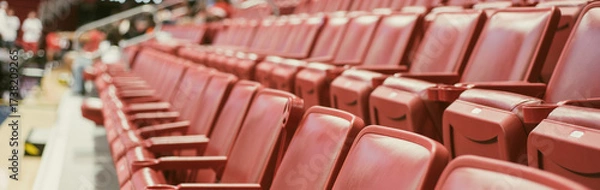 Fototapeta Panorama view folded red stadium chairs with visible seat numbers. Distant figures and banners hint at basketball warm-up or informal training session game at college stadium in Dallas, Texas