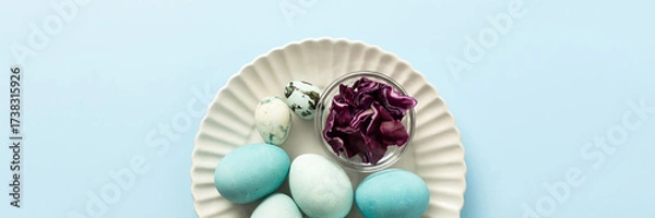 Fototapeta A plate holds several blue-painted Easter eggs and a couple of small patterned eggs, creating a festive atmosphere for the holiday celebration, small bowl of red cabbage, how to dye eggs blue, banner