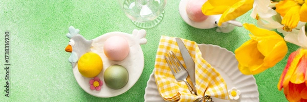 Fototapeta A beautifully arranged Easter table setting showcases a decorative egg nestled in a yellow napkin, surrounded by a glass of water and fresh flowers, perfect for holiday gatherings