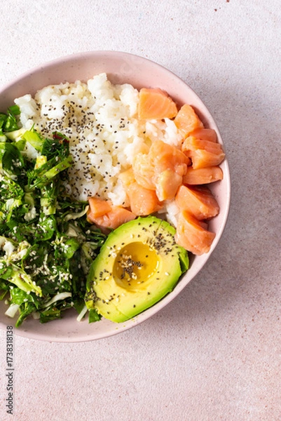 Fototapeta A nutritious breakfast bowl featuring rice, salmon, avocado, and fresh greens is presented beautifully in a bowl. Simple and healthy morning meal idea with vibrant colors