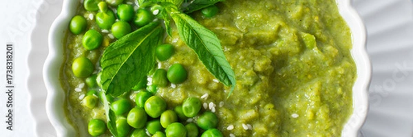 Fototapeta A bowl of vibrant green pea and broccoli soup is topped with fresh mint leaves for flavor. This healthy dish is perfect for a warm lunch or cozy dinner at home, banner