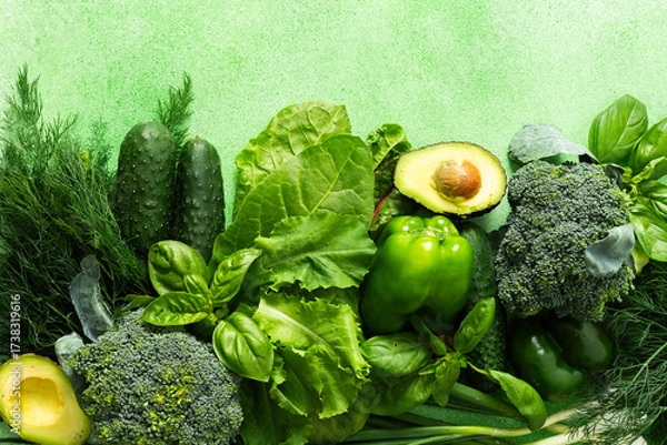 Fototapeta A vibrant collection of fresh green vegetables and herbs fills the scene, showcasing broccoli, cucumbers, lettuce, avocado, and various herbs like basil and dill, healthy eating