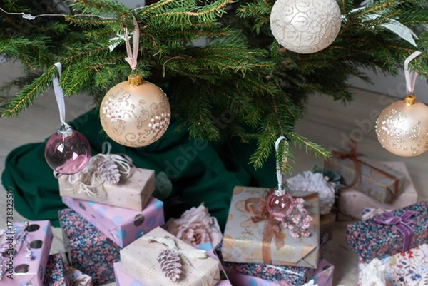 Fototapeta Vibrant pink and purple gift boxes with shiny ribbons rest under a Christmas tree adorned with glowing lights, creating a playful and joyful festive scene