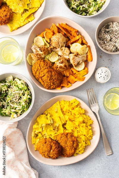 Fototapeta Enjoy a flavorful meal featuring rice topped with rhubarb fried eggs, baked sweet potato, and colorful veggies. Fresh salad and crispy meat fritters complete this delightful dish