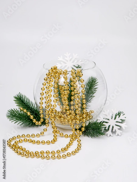 Obraz New Year's still life in a transparent round vase, a fir tree branch with white snowflakes and golden beads on a white background