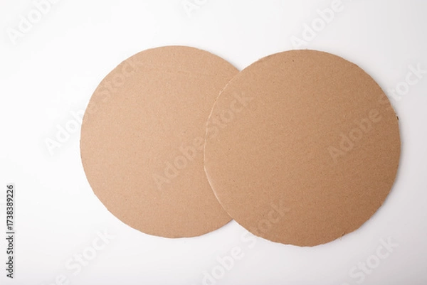 Fototapeta Two rough-edged cardboard circles on clean surface, useful for branding, product presentation, educational content, eco-friendly campaigns, and creative layout design.