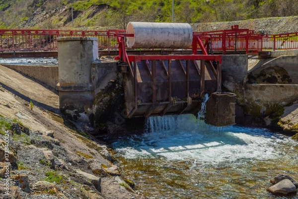 Fototapeta Water control structure releasing water in mountainous region