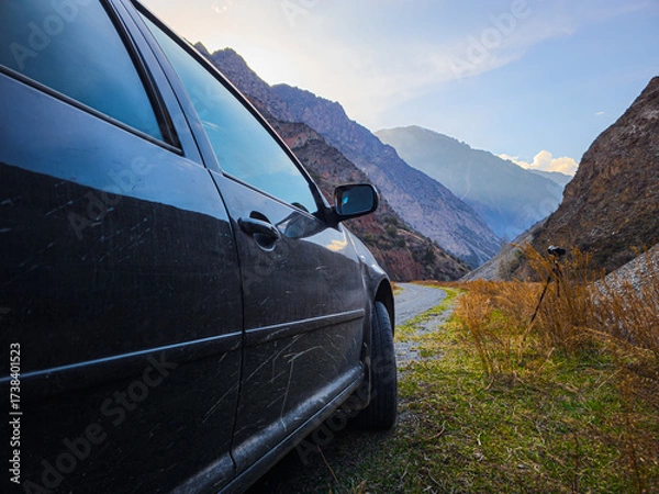 Fototapeta car on gravel road with camera on a tripod in mountainous region