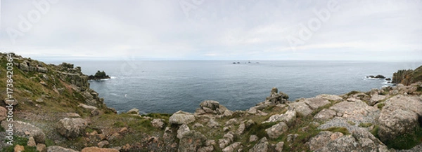 Obraz Panorama of Cornwall rocky shoreline, with cliffs near shore, Longships lightouse visible in distance