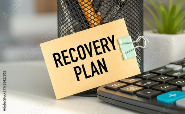 Fototapeta A clipboard with a sign that says Recovery Plan is on top of a calculator.