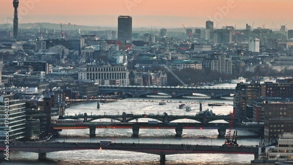 Obraz United Kingdom, London: Warm sunset colors reflecting on River Thames with bridges, buildings and skyscrapers of London's financial district at dusk, aerial view from a drone. Drone flight