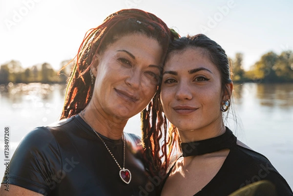 Fototapeta Two women with dreadlocks standing close, sharing a moment of affection by a lake