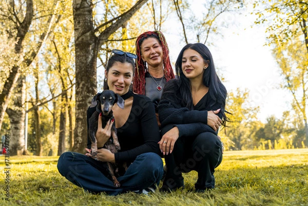 Fototapeta Family of mother and two daughters embracing their dachshund dog in a vibrant autumn park