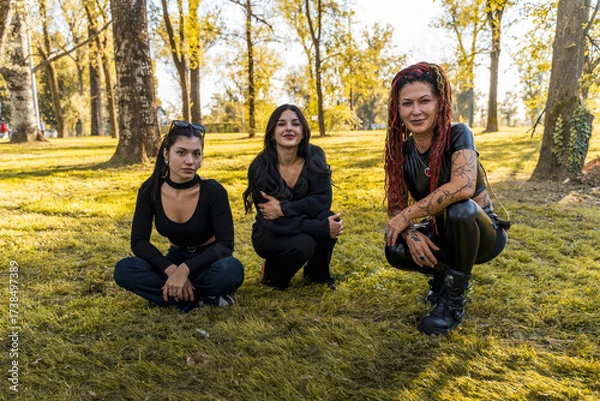 Fototapeta Diverse women with alternative fashion posing on grass, enjoying friendship in a park