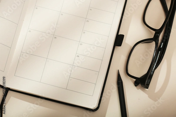 Fototapeta A diary next to glasses and a pencil, the concept of organising time