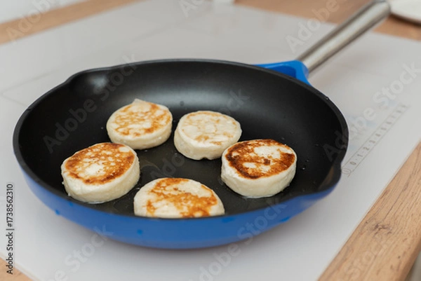 Fototapeta Cheesecakes are fried in a frying pan with a ruddy crust