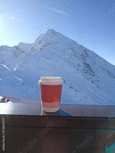 Fototapeta A red cup with a white lid sits on a wooden railing