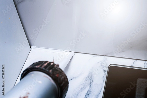 Fototapeta applying sealant to the gap between porcelain tiles to prevent debris from getting in and unsanitary conditions